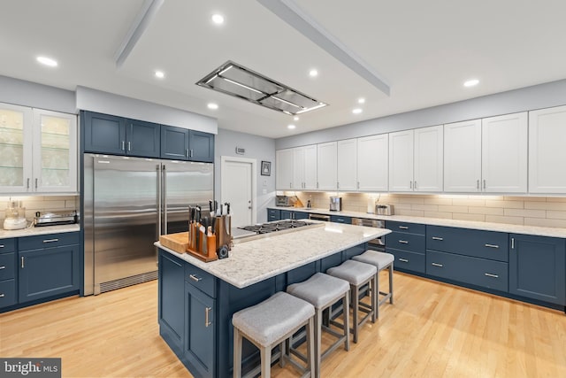 1419 Ramseur Ln, Winchester, VA 22601 - kitchen with stainless steel built in fridge, a breakfast bar area, blue cabinetry, decorative backsplash, and recessed lighting