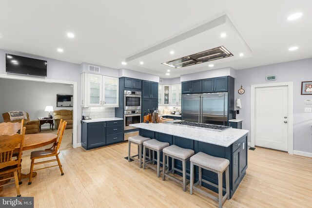 1419 Ramseur Ln, Winchester, VA 22601 - kitchen featuring appliances with stainless steel finishes, a breakfast bar, decorative backsplash, glass insert cabinets, and light wood-style flooring
