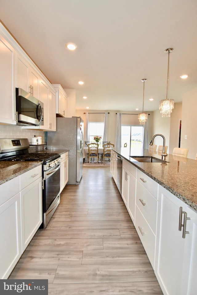35258 Wright Way, Millsboro, DE 19966 - kitchen with stainless steel appliances, a sink, white cabinets, a chandelier, and dark stone counters