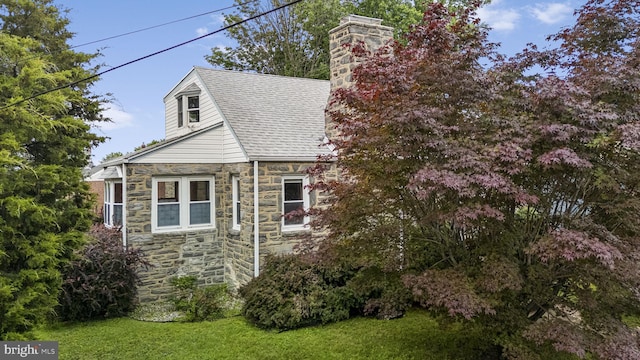 1217 Bullens Ln, Woodlyn, PA 19094 - view of home's exterior with stone siding, a chimney, a yard, and roof with shingles