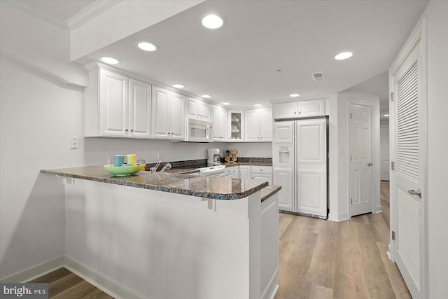 5901 Atlantic Ave Unit 411, Ocean City, MD 21842 - kitchen featuring white microwave, paneled fridge, a peninsula, white cabinetry, and light wood finished floors