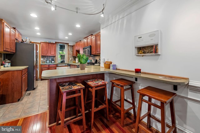 3310 Hudson St, Baltimore, MD 21224 - kitchen featuring stainless steel appliances, a peninsula, recessed lighting, a kitchen bar, and backsplash