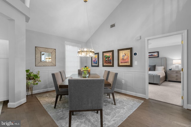 8820 Shining Oceans Way Unit 407, Columbia, MD 21045 - dining area with high vaulted ceiling, a chandelier, a decorative wall, wood finished floors, and a wainscoted wall