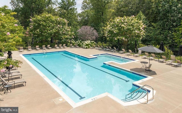 8820 Shining Oceans Way Unit 407, Columbia, MD 21045 - community pool featuring a patio area and view of wooded area