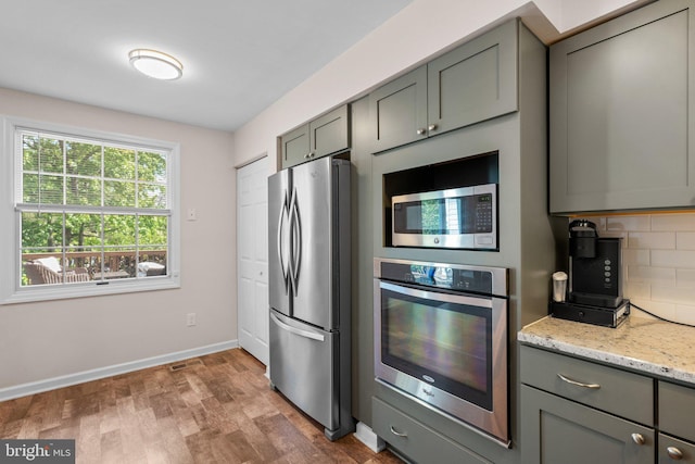 1328 Hollow Glen Ct, Curtis Bay, MD 21226 - kitchen with stainless steel appliances, gray cabinetry, wood finished floors, decorative backsplash, and light stone counters