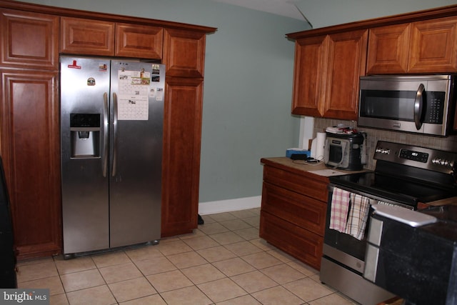 527 N 25th St, Reading, PA 19606 - kitchen featuring stainless steel appliances, backsplash, brown cabinets, light tile patterned floors, and baseboards