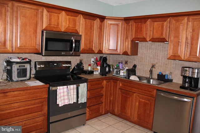 527 N 25th St, Reading, PA 19606 - kitchen featuring stainless steel appliances, brown cabinetry, tile counters, and backsplash