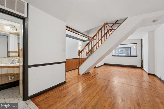 913 Tasker St, Philadelphia, PA 19148 - unfurnished living room with a sink, stairway, wood-type flooring, and baseboards