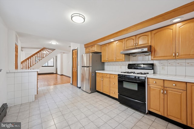 913 Tasker St, Philadelphia, PA 19148 - kitchen with gas stove, under cabinet range hood, freestanding refrigerator, backsplash, and a baseboard radiator