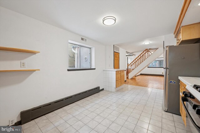 913 Tasker St, Philadelphia, PA 19148 - kitchen with gas range oven, a baseboard heating unit, light countertops, and light tile patterned floors