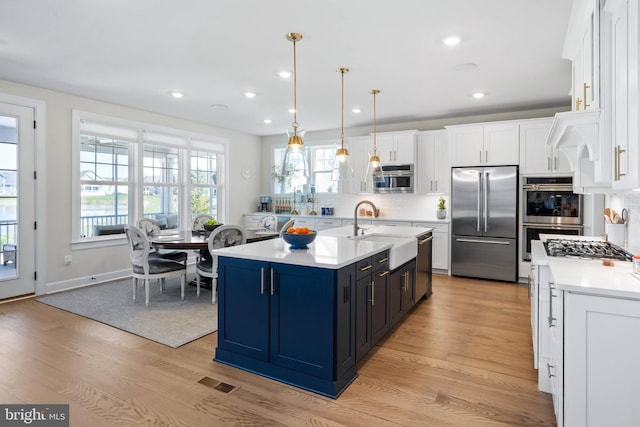 18234 Highwood Dr, Rehoboth Beach, DE 19971 - kitchen featuring appliances with stainless steel finishes, a sink, light wood-type flooring, white cabinetry, and recessed lighting