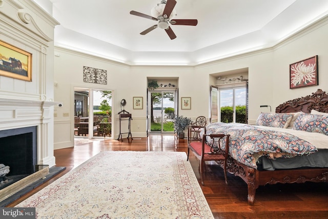 9791 Pintail Pl, Saint Michaels, MD 21663 - bedroom featuring access to outside, a tray ceiling, wood finished floors, a fireplace with raised hearth, and ceiling fan