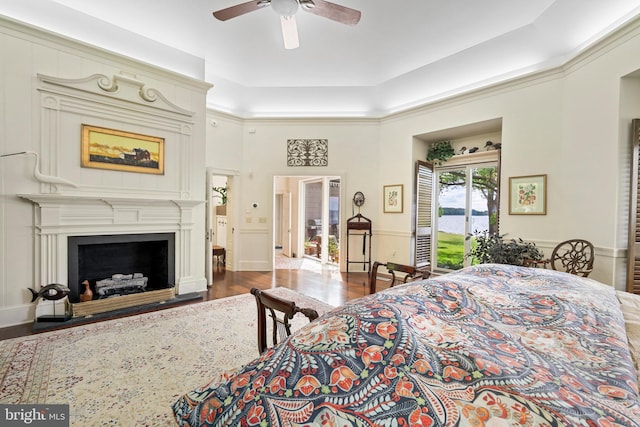 9791 Pintail Pl, Saint Michaels, MD 21663 - bedroom featuring access to outside, wood finished floors, a fireplace with flush hearth, ceiling fan, and a tray ceiling