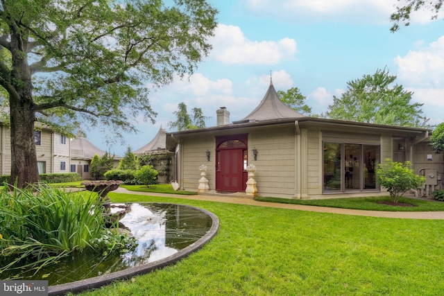 9791 Pintail Pl, Saint Michaels, MD 21663 - view of front of house with a front lawn, a chimney, and a small pond