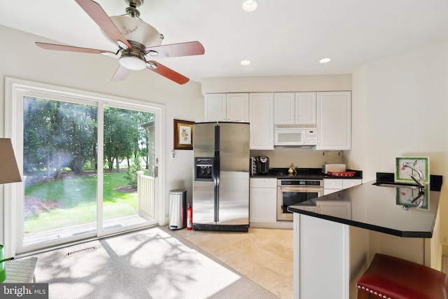 9791 Pintail Pl, Saint Michaels, MD 21663 - kitchen featuring stainless steel appliances, dark countertops, white cabinetry, light tile patterned floors, and recessed lighting