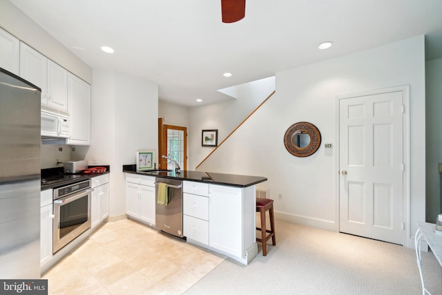 9791 Pintail Pl, Saint Michaels, MD 21663 - kitchen with appliances with stainless steel finishes, a peninsula, white cabinets, dark countertops, and a breakfast bar