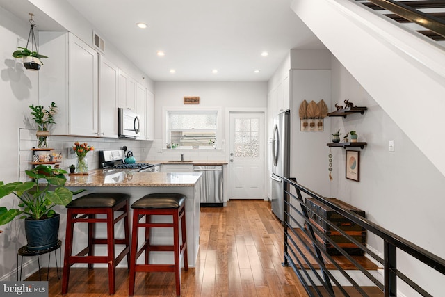 2117 Latona St, Philadelphia, PA 19146 - kitchen featuring stainless steel appliances, a peninsula, light stone counters, recessed lighting, and white cabinets