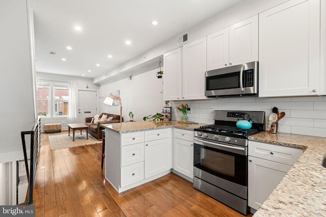 2117 Latona St, Philadelphia, PA 19146 - kitchen with stainless steel appliances, a peninsula, white cabinets, light wood-style flooring, and open floor plan