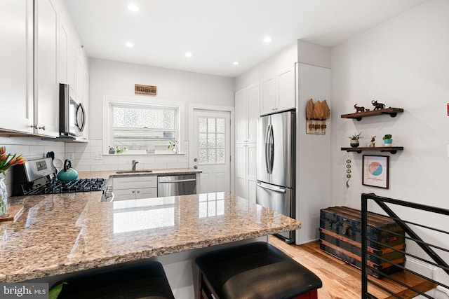 2117 Latona St, Philadelphia, PA 19146 - kitchen with stainless steel appliances, a sink, a peninsula, light stone countertops, and recessed lighting