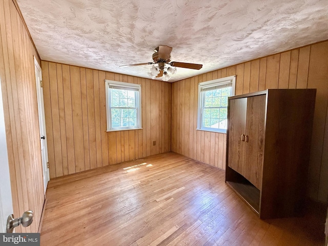 9733 Narragansett Pkwy, College Park, MD 20740 - unfurnished bedroom featuring multiple windows, light wood-style floors, wooden walls, ceiling fan, and a closet