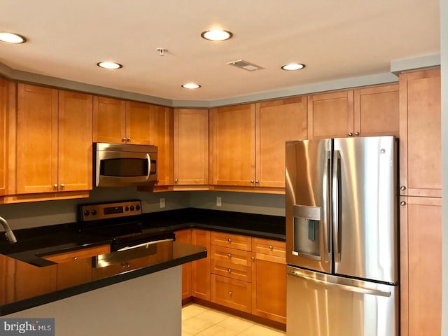 1111 11th St NW Unit 307, Washington, DC 20001 - kitchen featuring appliances with stainless steel finishes, dark countertops, brown cabinets, recessed lighting, and light tile patterned floors