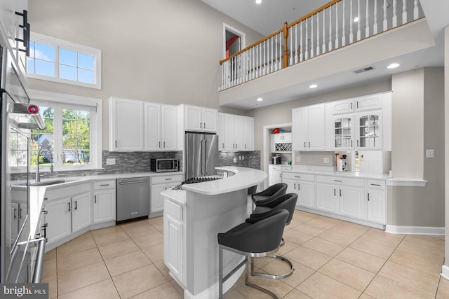 12801 Willow Marsh Ln, Bowie, MD 20720 - kitchen with stainless steel appliances, a high ceiling, a center island, tasteful backsplash, and light tile patterned floors