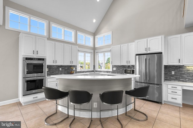 12801 Willow Marsh Ln, Bowie, MD 20720 - kitchen with stainless steel appliances, a kitchen breakfast bar, decorative backsplash, white cabinets, and high vaulted ceiling