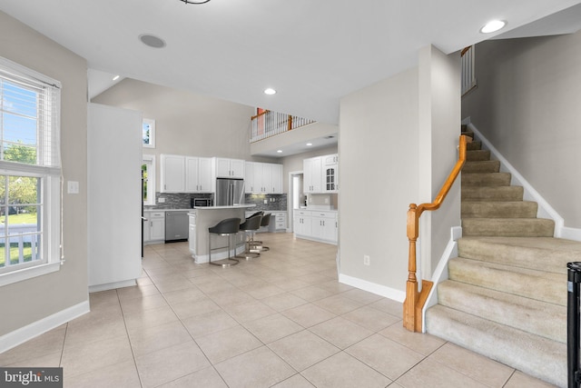 12801 Willow Marsh Ln, Bowie, MD 20720 - kitchen with appliances with stainless steel finishes, a breakfast bar area, decorative backsplash, white cabinets, and a high ceiling