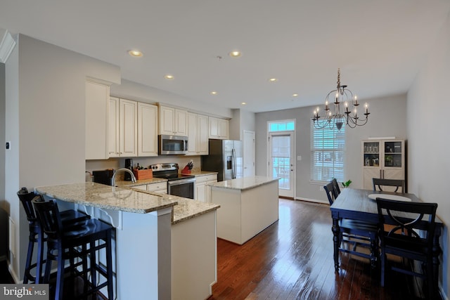 888 S Macon St, Baltimore, MD 21224 - kitchen with appliances with stainless steel finishes, a center island, light stone countertops, a chandelier, and dark wood-type flooring