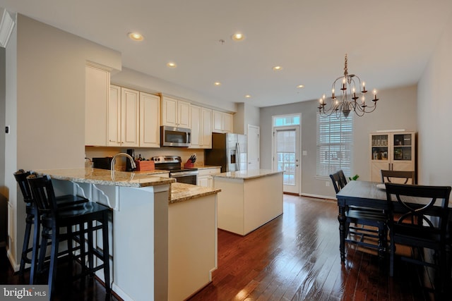 888 S Macon St, Baltimore, MD 21224 - kitchen featuring stainless steel appliances, a kitchen island, dark wood finished floors, a chandelier, and light stone countertops