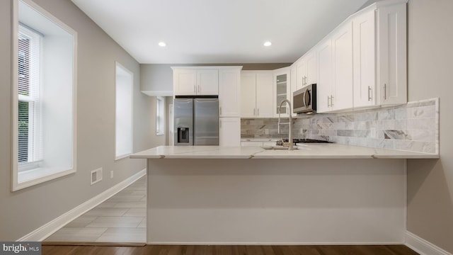 7804 Ardleigh St, Philadelphia, PA 19118 - kitchen featuring stainless steel appliances, decorative backsplash, a peninsula, white cabinets, and recessed lighting