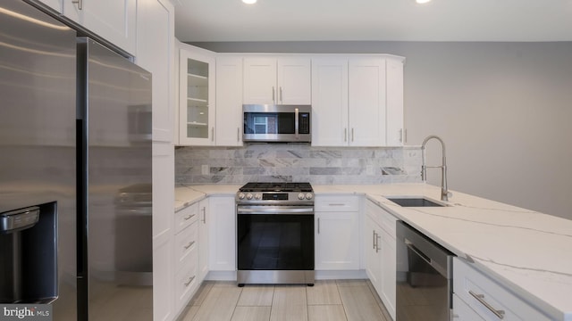 7804 Ardleigh St, Philadelphia, PA 19118 - kitchen with appliances with stainless steel finishes, a sink, backsplash, white cabinets, and light stone counters