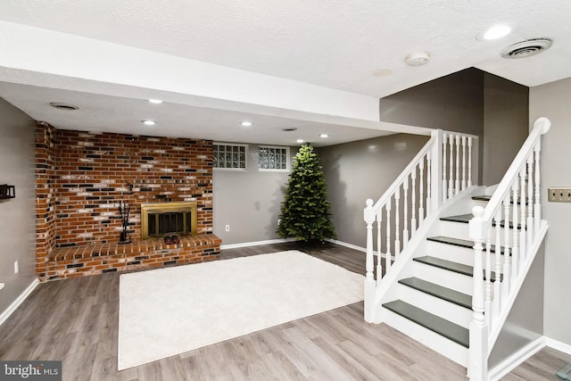 10 Bantry Ct, Baltimore, MD 21237 - unfurnished living room featuring wood finished floors, baseboards, a brick fireplace, stairway, and a textured ceiling