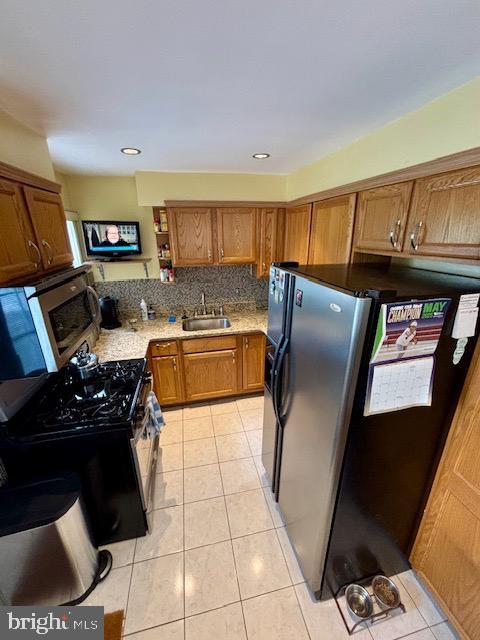 4116 Ellis St, Capitol Heights, MD 20743 - kitchen with appliances with stainless steel finishes, a sink, brown cabinetry, light tile patterned floors, and recessed lighting
