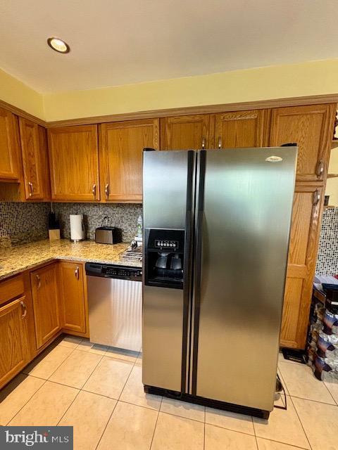 4116 Ellis St, Capitol Heights, MD 20743 - kitchen featuring fridge with ice dispenser, stainless steel dishwasher, brown cabinets, light tile patterned floors, and light stone countertops