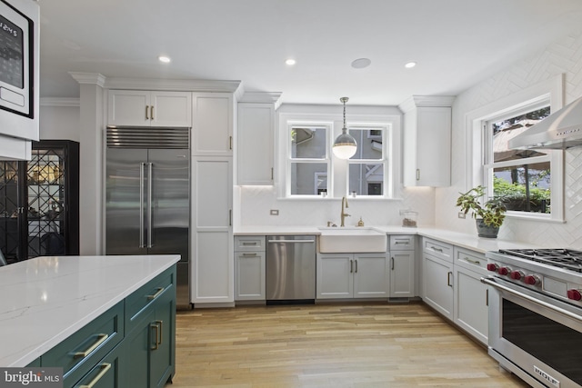 6200 Broad Branch Rd NW, Washington, DC 20015 - kitchen featuring high end appliances, a sink, light wood-type flooring, backsplash, and hanging light fixtures