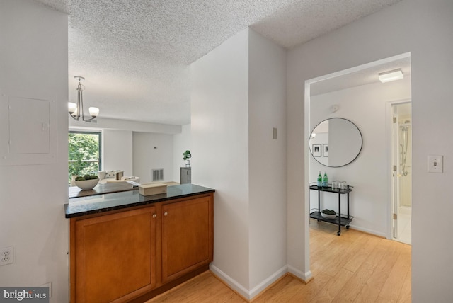 3800 Powell Ln Unit 629, Falls Church, VA 22041 - kitchen featuring a textured ceiling, light wood-type flooring, dark countertops, brown cabinets, and a chandelier