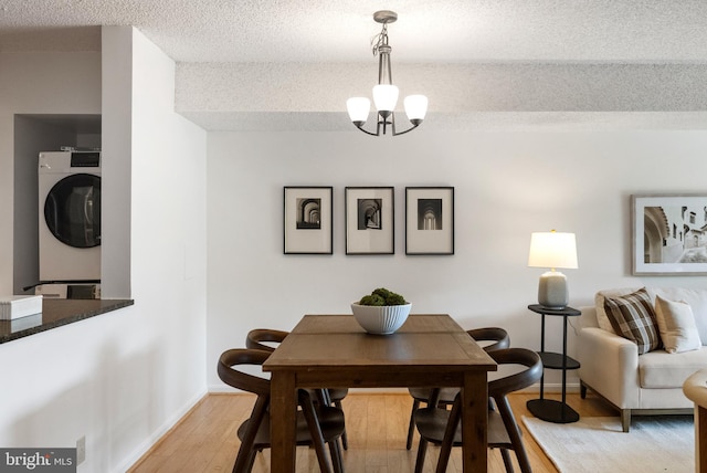 3800 Powell Ln Unit 629, Falls Church, VA 22041 - dining space with estacked washer and dryer, a textured ceiling, light wood finished floors, baseboards, and a chandelier