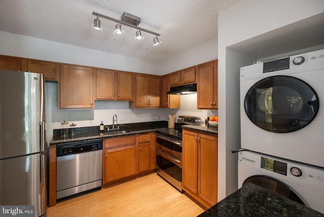 3800 Powell Ln Unit 629, Falls Church, VA 22041 - kitchen featuring appliances with stainless steel finishes, estacked washer and dryer, under cabinet range hood, a sink, and light wood-style flooring