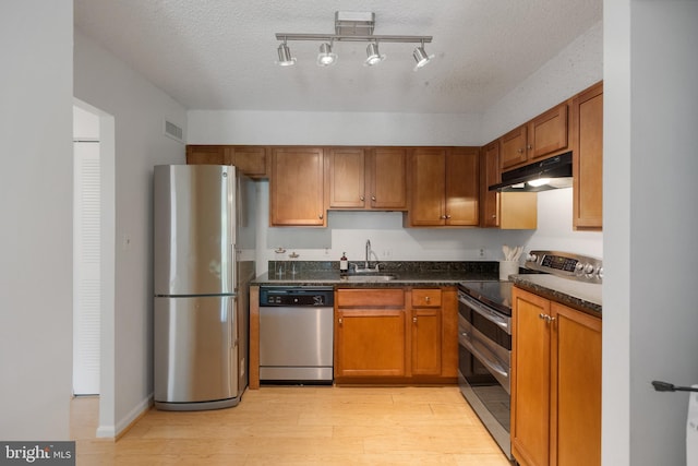 3800 Powell Ln Unit 629, Falls Church, VA 22041 - kitchen featuring stainless steel appliances, under cabinet range hood, light wood-type flooring, brown cabinetry, and a sink