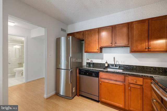 3800 Powell Ln Unit 629, Falls Church, VA 22041 - kitchen featuring appliances with stainless steel finishes, light wood-type flooring, a sink, brown cabinets, and a textured ceiling