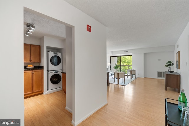 3800 Powell Ln Unit 629, Falls Church, VA 22041 - hall with stacked washer / dryer, a textured ceiling, light wood-style floors, and baseboards