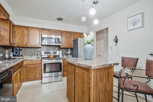 9803 Luke Ct, Upper Marlboro, MD 20772 - kitchen featuring stainless steel appliances, brown cabinetry, and decorative backsplash