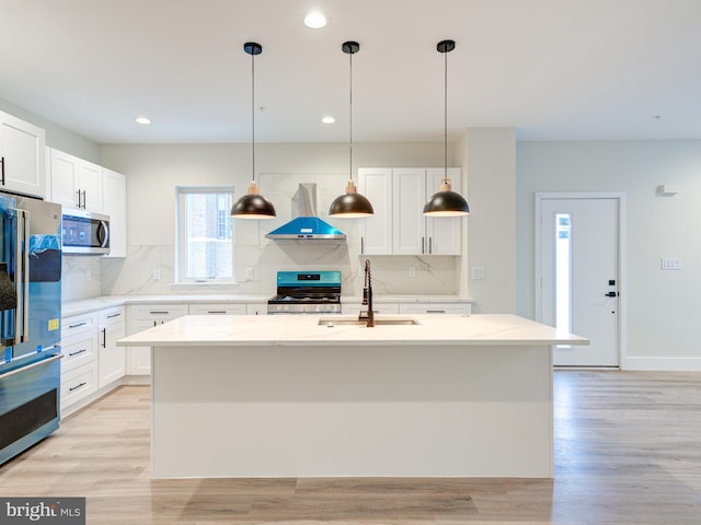 632 Moyer St, Philadelphia, PA 19125 - kitchen with stainless steel appliances, wall chimney range hood, a sink, light wood finished floors, and a center island with sink