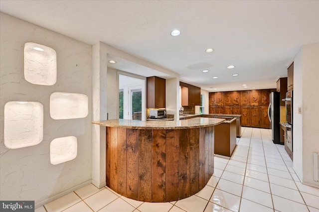 22 Woodholme Village Ct, Baltimore, MD 21208 - kitchen featuring brown cabinetry, stainless steel appliances, recessed lighting, light stone countertops, and light tile patterned floors