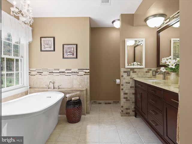 6805 Spout Ln, Fairfax Station, VA 22039 - bathroom featuring tile walls, a freestanding tub, double vanity, tile patterned flooring, and a wainscoted wall