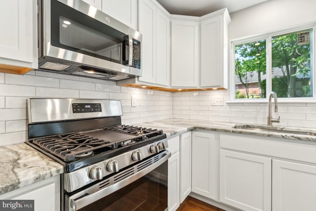 3713 Deming Dr, Suitland, MD 20746 - kitchen featuring appliances with stainless steel finishes, a sink, white cabinets, tasteful backsplash, and light stone counters