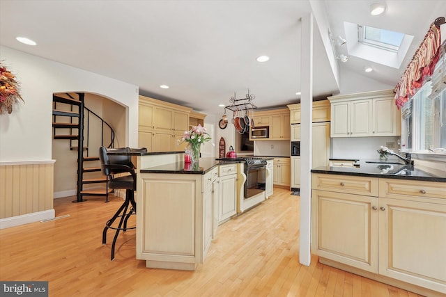 609 Ederer Ln, Ambler, PA 19002 - kitchen featuring built in appliances, cream cabinets, a skylight, a kitchen bar, and vaulted ceiling
