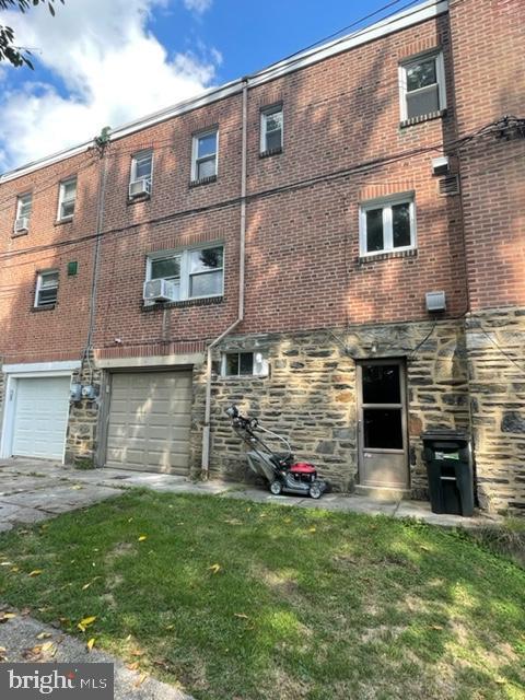 2632 Lenape Rd, Philadelphia, PA 19131 - rear view of house with stone siding, concrete driveway, an attached garage, and brick siding