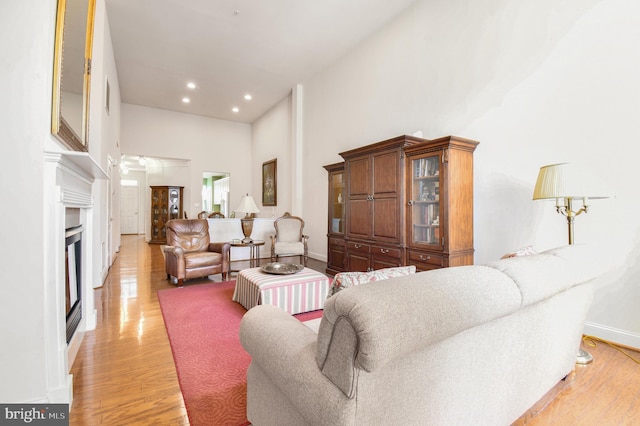 7207 Ivy Bank Rd, Laurel, MD 20707 - living area featuring a towering ceiling, light wood-style floors, baseboards, recessed lighting, and a glass covered fireplace